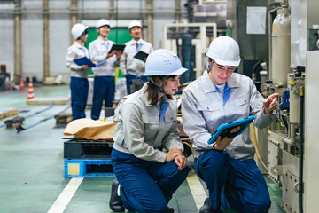 工場現場で作業員の声に耳を傾けメモを取る開発者