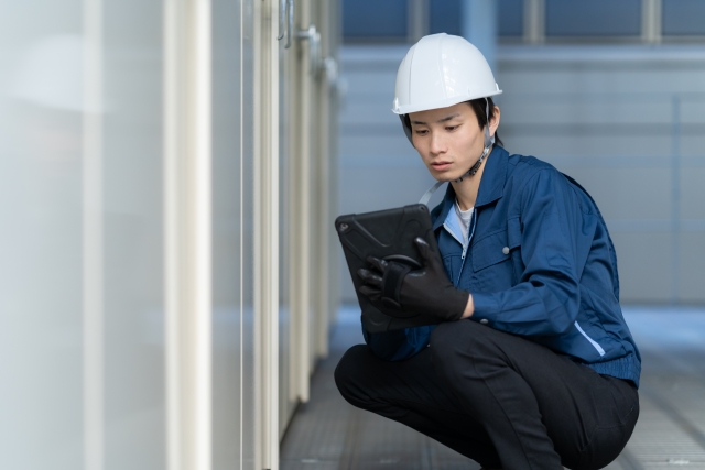 作業用手袋をつけたままタブレット画面を操作しようとする工場作業員