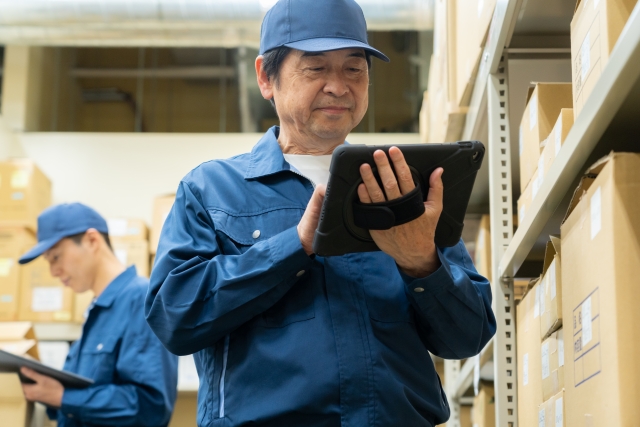タブレットを手に持ちながら困惑した表情のベテラン作業員